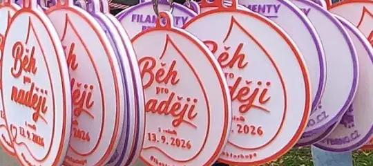 Detail bílých medailí s červeným reliéfem Běh pro naději
